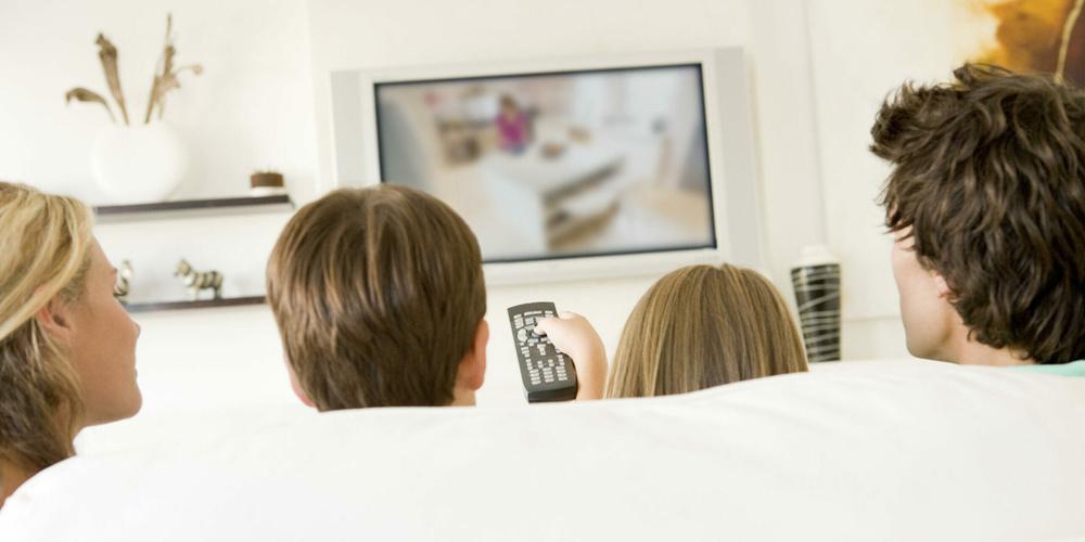 Family in living room with remote control and flat screen televi